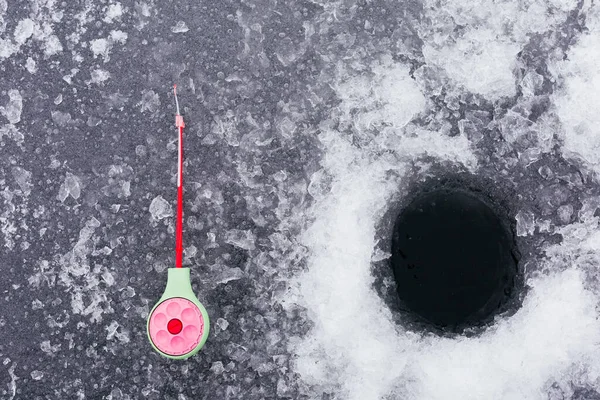 Winter fishing. Fishing rod for ice fishing. Tackle and ice hole. Background. Ice fishing concept. High quality photo