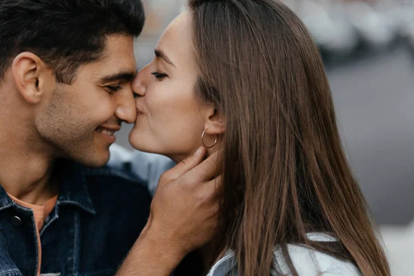 年轻美丽的女孩亲吻他男朋友的鼻子 在城市里相爱的夫妻城市的爱情 高质量的照片 — 图库照片