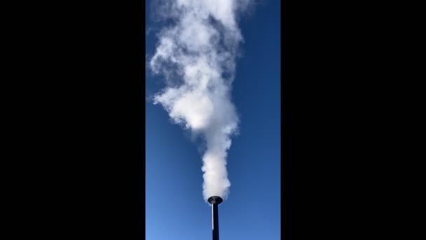 Λευκός καπνός ενάντια στον γαλάζιο ουρανό. Ατμοσφαιρική ρύπανση από καπνό που βγαίνει από την καμινάδα. Κάθετη μορφή. — Αρχείο Βίντεο