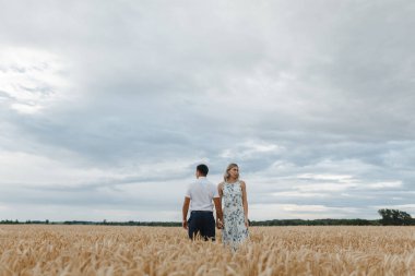 Buğday tarlasında el ele tutuşan çiftler. Erkek ve kadın buğday giyinmiş.