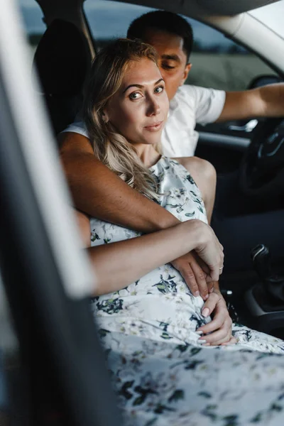 Happy couple in a car. Embracing man and woman in a car. High quality photo