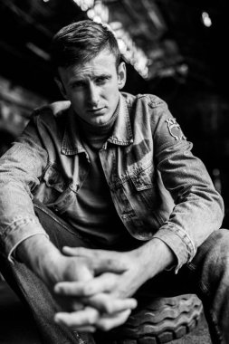 Kot ceketli zalim adam oturuyor ve parmaklarını kenetliyor. Erkek portresi