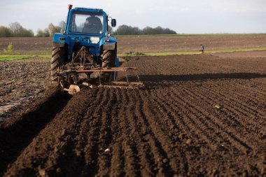 An old blue tractor plows the land. Place for your text