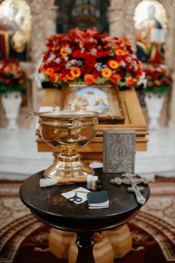  Kilisedeki vaftiz malzemeleri masadaki çiçeklerin arka planına karşı.