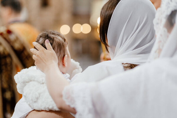  The sacrament of baptism. Mom strokes the child on the head in church.