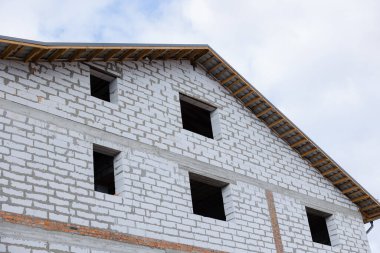 Bir inşaat alanında, tamamlanmamış bir bina ayakta duruyor, açıkta duran duvarlar ve açıklıklar son rötuşları bekliyor..