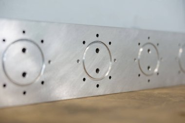 Yarı bitmiş bir binada, metal parçaları ortaya çıkarır. Şişe kalıpları ve kontrol düğmeleri için tasarlanmış, karmaşık detaylar sergiliyor..