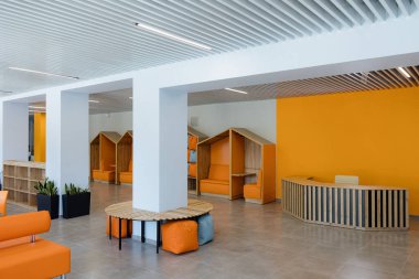 Geniş bir ofis alanı parlak turuncu duvarlar, rahat oturma köşeleri ve davetkar bir ortam yaratan minimalist kabul masası içerir..