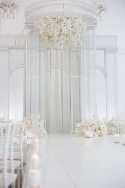 Güzel bir düğün sunağı beyaz çiçeklerle süslenir, yumuşak ışıklandırma, ve büyüleyici bir atmosfer, evlilik yeminleri için mükemmel..