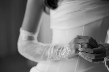 Enfes bir gelinlik giymiş bir gelin, alyansını narin elleriyle ayarlar. Törene hazırlanırken zarafet ve heyecan saçar..