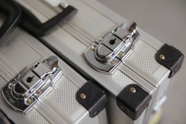 İki gümüş kasa yan yana oturur, parlak kilitleri yumuşak ışık altında parıldar, ilerideki yolculuklarında sırlarla dolu..