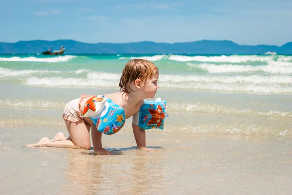 Little girl crawls to something in the sea — Stock Photo, Image