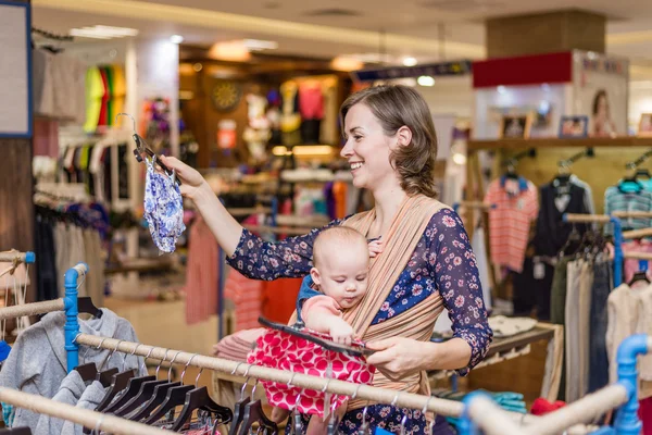 Jovem mulher com bebê em uma funda no centro comercial — Fotografia de Stock