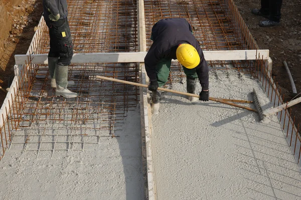 Trabajadores de la construcción con casco amarillo en un piso de hormigón — Foto de Stock