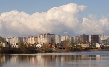 Güneşli bir günde gölün kıyısından şehirdeki konut binalarına bakın..