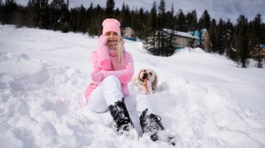 Bir kız ve labrador köpeği karda oturuyor.