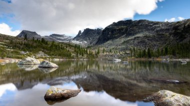 Ergaki Gölü doğa parkında dağların arasında gökyüzünün sudaki yansımaları.