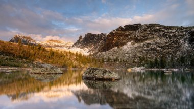 Doğal parktaki Ergaki Gölü dağların arasında günbatımında sudaki dağların sarı sonbahar yansımaları.