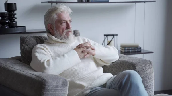 A manly, confident old man is sitting on a chair. A man sits with a thoughtful look — Stock Photo, Image