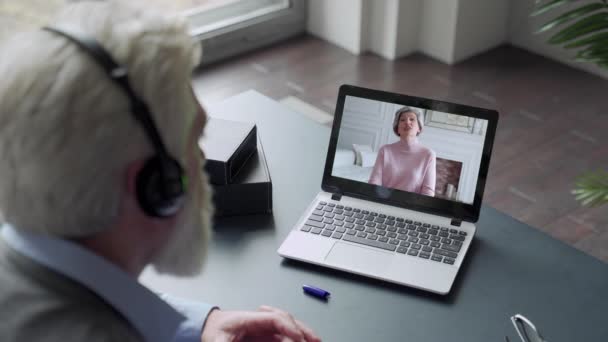 Sobre a visão do ombro de um homem idoso chamada de vídeo para a esposa usando um laptop. O conceito de videochamada familiar — Vídeo de Stock