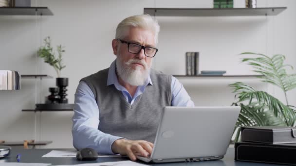 Hombre de edad avanzada cansado sentarse en el escritorio quitarse las gafas de reposo de la computadora portátil reduce la fatiga visual después de un largo uso moderno del dispositivo. — Vídeo de stock