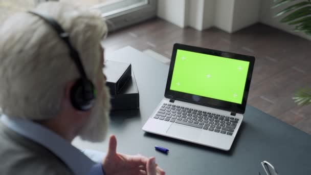 Elderly mature woman with gray hair and a video call on her Laptop. Laptop with a green screen — Stock Video