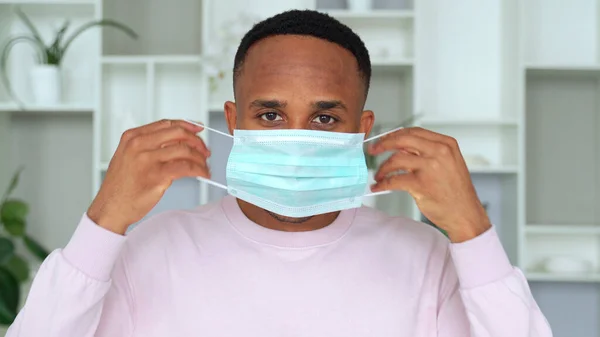 Retrato de homem afro-americano colocando máscara médica antes de sair como respirador de proteção contra doenças — Fotografia de Stock