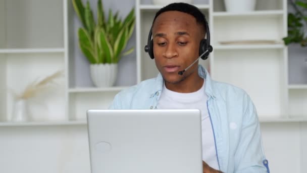 Konzentrierter schwarzer Berater mit Headset blickt auf einen Laptop — Stockvideo