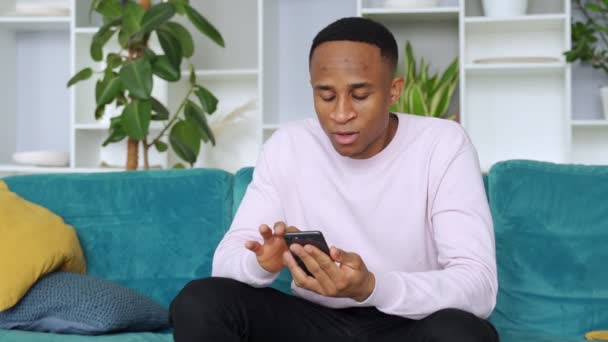 Ganador hombre negro celebración de teléfono inteligente sensación eufórica con móvil juego de apuesta en línea ganar — Vídeo de stock