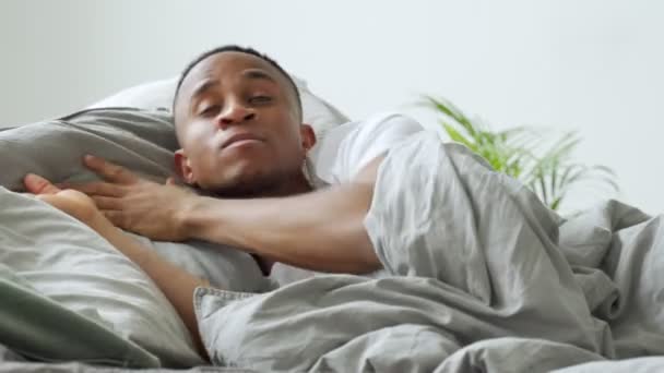 Joven afroamericano reuniéndose amanecer en la cama, sufriendo de insomnio — Vídeo de stock