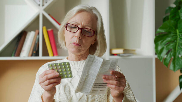 Old woman reading medicine pills instruction. Senior lady reading instruction pills