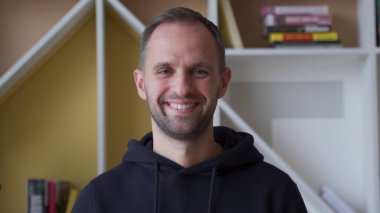 Ofiste dururken gülümseyen yakışıklı bir gencin portresi.