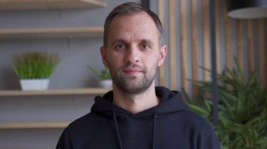 Ofiste dururken gülümseyen yakışıklı bir gencin portresi.