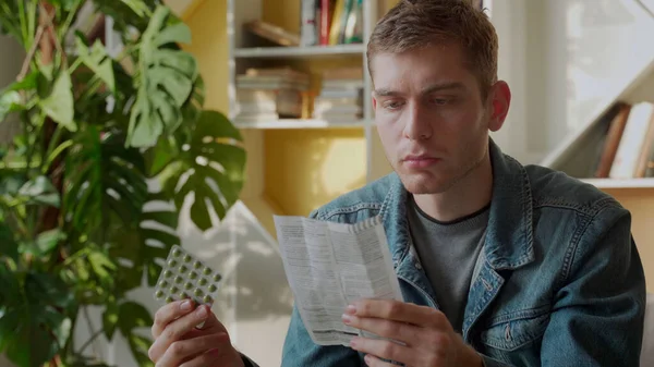 A man reads the instructions for pills sitting at home — Stock Photo, Image