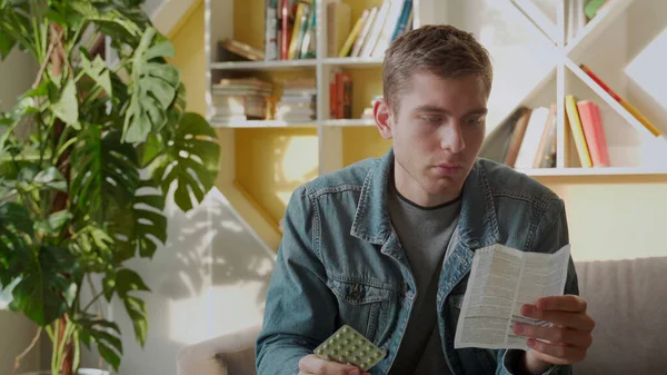 A man reads the instructions for pills sitting at home — Stock Photo, Image