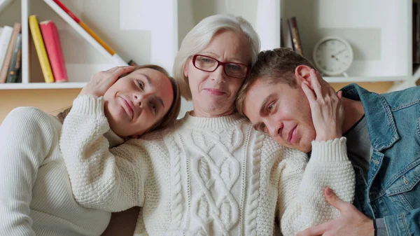 Sonriendo mamá anciana abrazando a su hija e hijo mientras está sentada en casa en el sofá — Foto de Stock