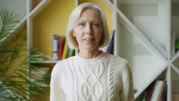 Souriant âge moyen mature femme aux cheveux gris regardant la caméra, heureuse vieille dame posant à la maison intérieure — Video