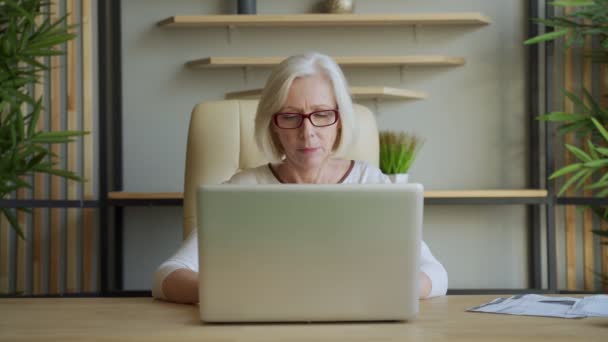 Retrato de una mujer mayor sonriente trabajando computadora portátil en interiores — Vídeo de stock