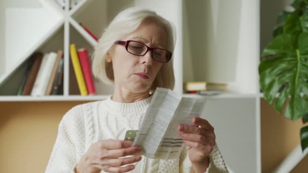 Alte Frau liest Medikamentenanleitung. Seniorin liest Anleitung vor — Stockvideo