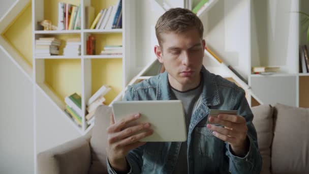 Online store concept-un uomo sorridente con tablet e carta di credito fa acquisti a casa — Video Stock