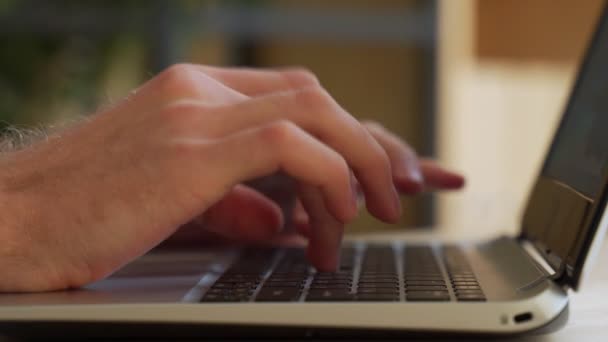 Közelkép férfi kezekről, akik laptopon gépelnek, miközben bent ülnek az irodában. Férfi ujjak koppintás és sms-ezés a számítógép billentyűzetén, miközben dolgozik a szekrényben. — Stock videók