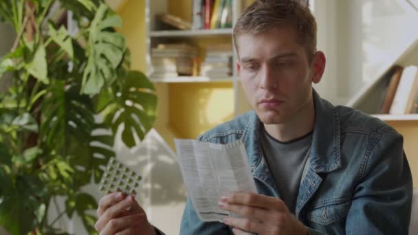 En man läser instruktionerna för piller som sitter hemma — Stockvideo