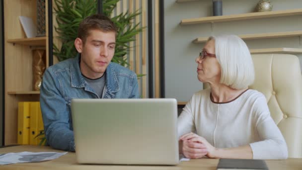 Ältere Geschäftsfrau kommuniziert mit Geschäftsmann mittleren Alters, diskutiert Arbeitsfragen, schaut auf Laptop-Bildschirm, Management verteilt Aufgaben für Mitarbeiter — Stockvideo