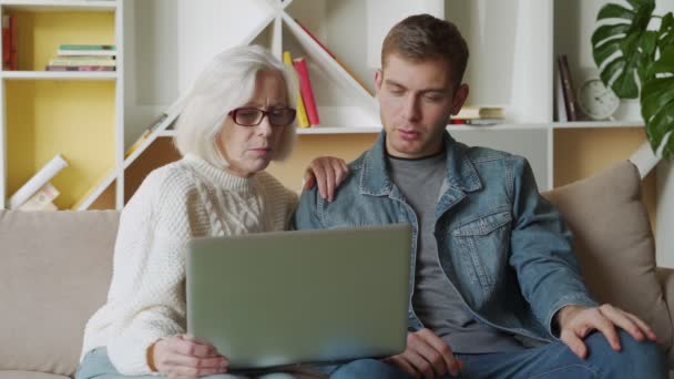 Pria paruh baya membantu ibunya menggunakan laptop di rumah. — Stok Video