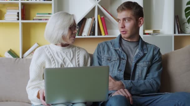 Mann lehrt seine Mutter mit Laptop zu Hause, Technologiekonzept. — Stockvideo