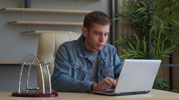 Een zakenman kijkt naar het computerscherm in het kantoor. Moe zakenman spelen met kinetische ballen — Stockvideo