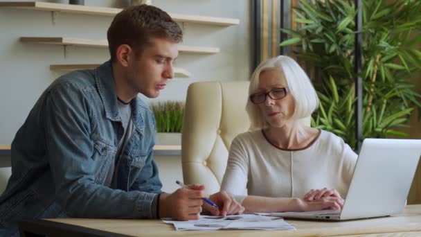 Ältere Geschäftsfrau kommuniziert mit Geschäftsmann mittleren Alters, diskutiert Arbeitsfragen, schaut auf Laptop-Bildschirm, Management verteilt Aufgaben für Mitarbeiter — Stockvideo