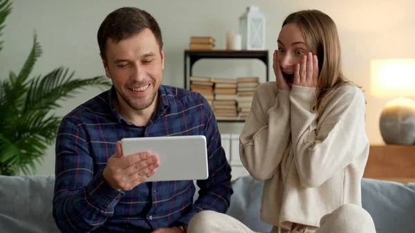 Aufgeregtes glückliches Familienpaar blickt auf digitales Tablet und fühlt sich von Lottogewinn überglücklich. — Stockfoto