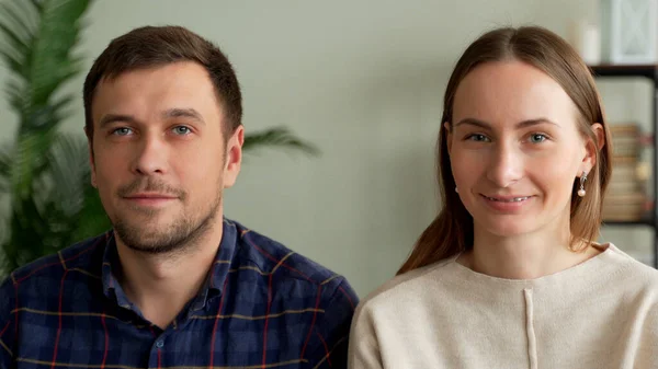 Портрет молодой пары, сидящей на диване. Пара, смотрящая в камеру — стоковое фото