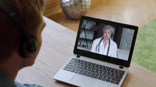 Adam çevrimiçi kadın doktorla görüntülü görüşme yapıyor. Sanal webcam sohbet uygulamasındaki uzaktan hasta danışma görüntülü konuşma. Omuz üstü bilgisayar ekran görüntüsü. — Stok video